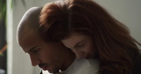 Young couple embracing each other while using laptop in living room Stock Footage 63374196