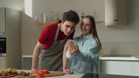 Young Couple Engaged In Cooking While Consulting a Smartphone Recipe in Modern Stockbeeldmateriaal 274551906