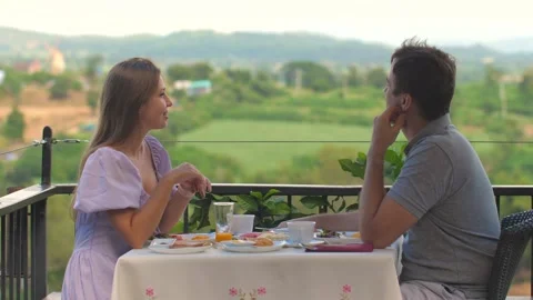Young couple enjoying breakfast date while sitting on outdoor terrace Stock Footage 281186299