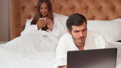 Young couple enjoying tech time in a cozy hotel room Stock Footage 311537308