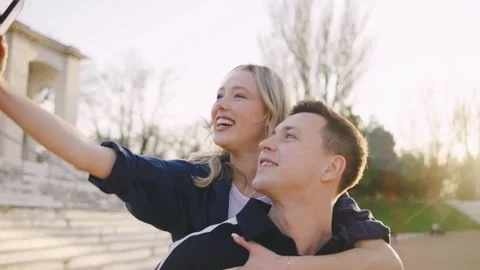 Young couple enjoys capturing a fun selfie together on a sunny day at a historic Stock Footage 314404739