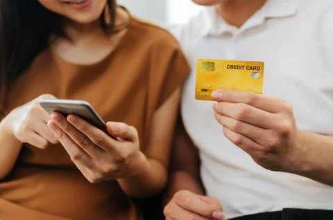 Young couple entering security code on mobile smart phone and credit card Stock-Fotos