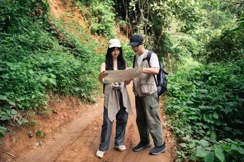 Young couple exploring forest trail using map for navigation during outdoor.. Stock Photos