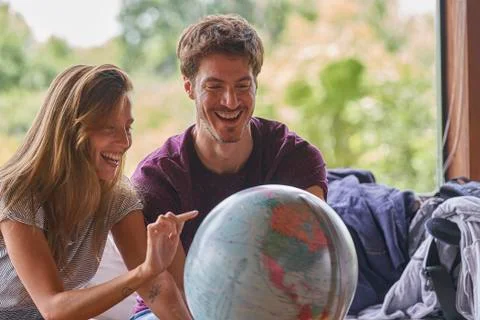 Young couple exploring world globe while sitting on sofa Stockfoto's