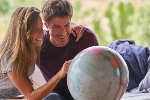 Young couple exploring world globe while sitting on sofa Stockfoto's