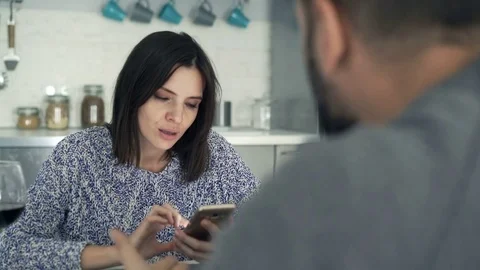 Young couple fighting, arguing by table at home, man using smartphone, 4K Stock Footage 69780695