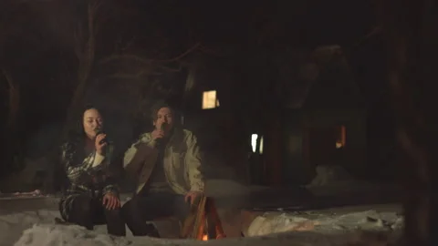 Young couple by the fire with beer. Видео 106458809