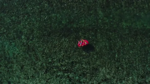 Young couple float in red heart shaped inner tubes in Tavarua Fiji. Stock Footage 135224350