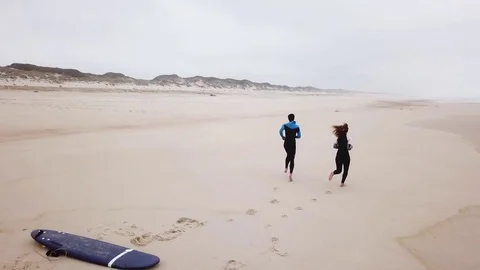 Young couple of friendly surfers wearing wetsuit Stock Footage