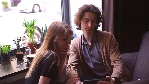 A young couple with gadget in cafe Stock Footage 76198217