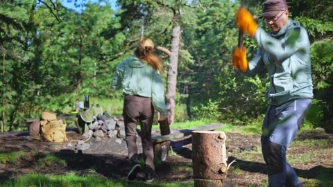 Young couple grilling sausages and burgers over campfire Vidéo 330397953