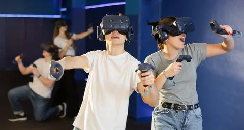 Young couple with handheld controllers and VR glasses playing game Stock Photos