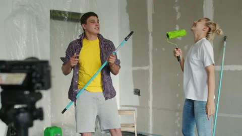 A young couple has fun shooting themselves on a camera on a tripod, while Stock Footage 139921216
