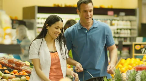 A young couple has fun shopping together in a produce section of a grocery store Stock Footage 34003675