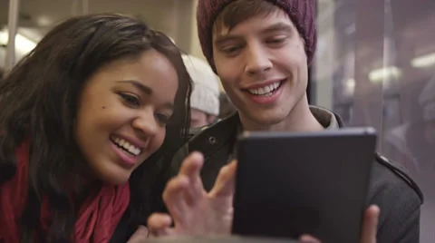 A young couple has a good time on the bus playing with their digital tablet Video stock 34017557