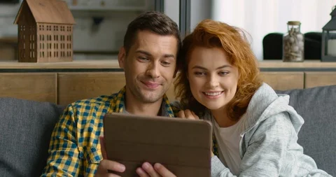 Young couple has a video chat on tablet computer, showing V signs, close up Stock Footage 114638538