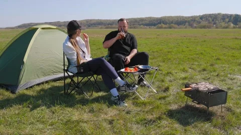 Young couple having barbecue while camping in nature Stockbeeldmateriaal 344606676