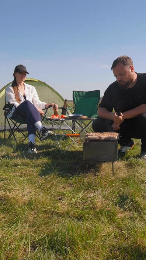 Young couple having barbecue while camping in nature 動画素材 344606677