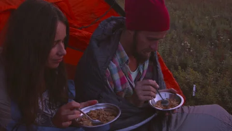 Young couple having dinner in the evening while sitting in a tent. Video stock 116925282