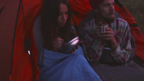 Young couple having dinner in the evening while sitting in a tent. Stock Footage 116928103