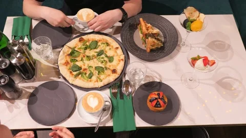 A young couple is having dinner at a restaurant. Coffee. Pizza. Stock Footage 138486942