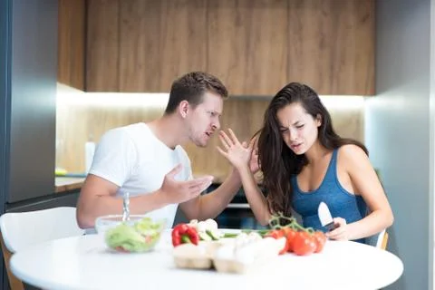 Young couple having fight while cooking breakfast in the kitchen husband shouts Stock Photos