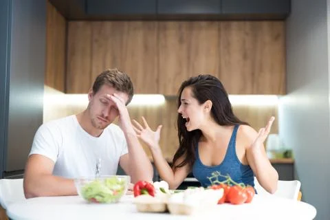 Young couple having fight while cooking breakfast in the kitchen wife shouts Foto stock