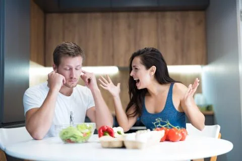 Young couple having fight while cooking breakfast in the kitchen wife shouts Stock Photos