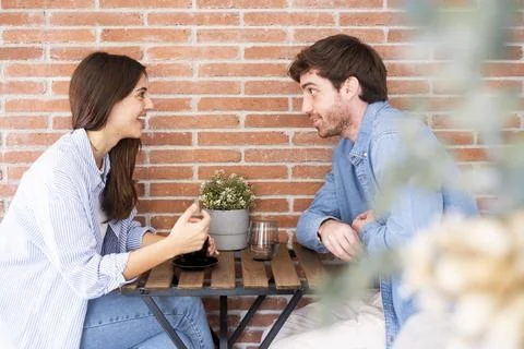 Young couple having a friendly coffee conversation at a cozy brick-walled c.. Stock Photos