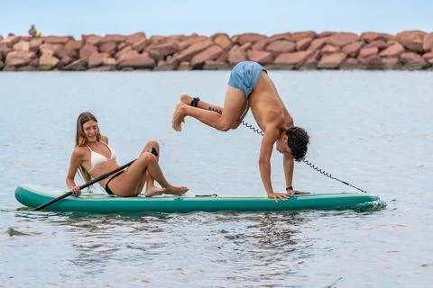 Young couple having fun doing handstand on paddle board Stock Photos