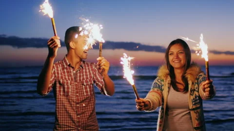 Young couple having fun with fireworks in the hands. Fireworks lit the pair Stock Footage 67624395