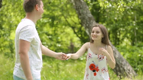 Young couple having fun on the green field in the spring or summer, general plan Stock Footage 85856928