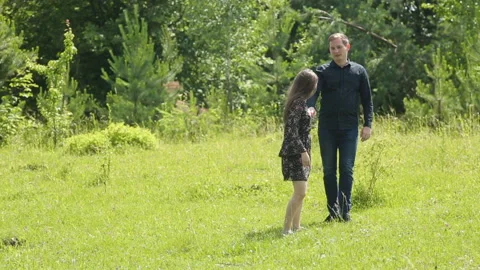 Young couple having fun on the green field in the spring or summer, general plan Stock Footage 86197712