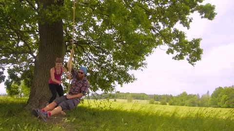 Young couple having fun on a outdoor swing on  a tree Stock Footage 78195062