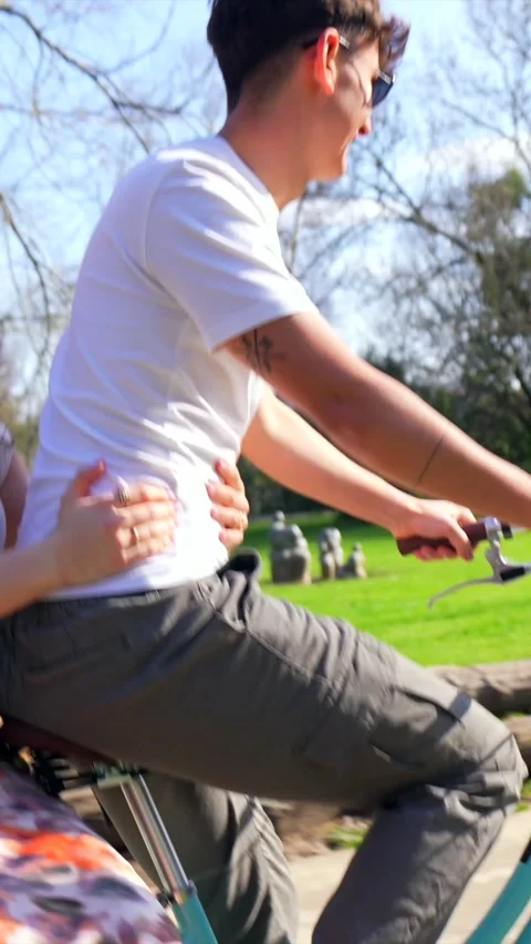 Young couple having fun riding bicycle in park Stock Footage 303485101
