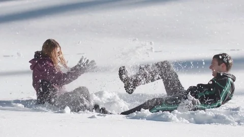 Young couple having fun sitting in high snow and throwing snow at each other Vídeo Stock 85077456