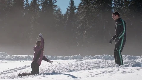 Young couple having a fun snow fight and fall over on a sunny day Vídeo Stock 85077367
