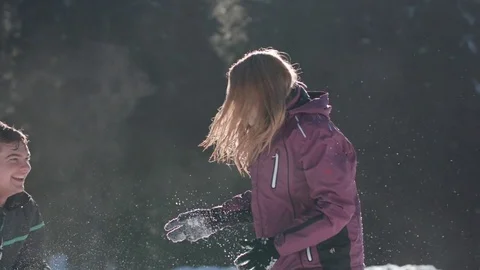 Young couple having a fun snowball fight and fall over on a sunny day Vídeo Stock 85076979