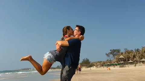 Young couple having fun spinning around and kissing on the beach. Slow motion Stock Footage 50591107