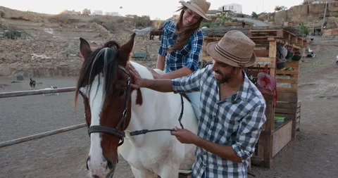 Young couple having fun with their horse inside farm ranch Stock Footage 145428239