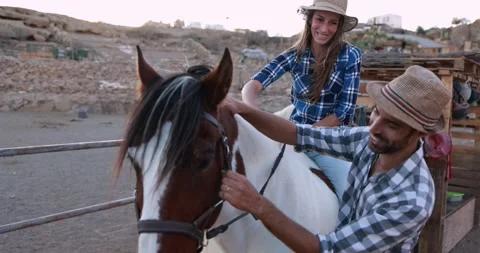 Young couple having fun with their horse inside farm ranch Stock Footage 145428294