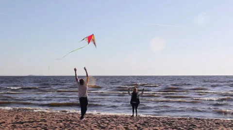 Young Couple Having Fun Trying To Send Colorful Kite In Flight Stock Footage 64863694