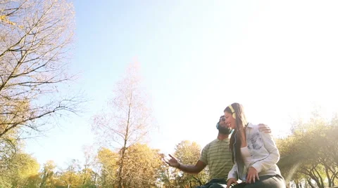 Young couple having fun while listening to music on headphones in park Stock Footage 59554767