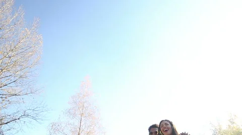 Young couple having fun while listening to music on headphones in park Stock Footage 59554778