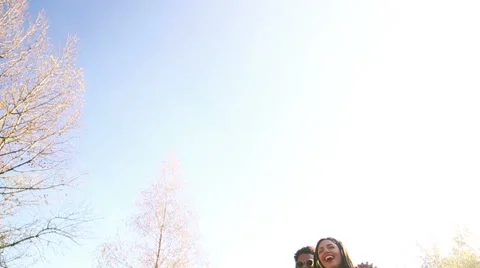 Young couple having fun while listening to music on headphones in park Stock Footage 59554779