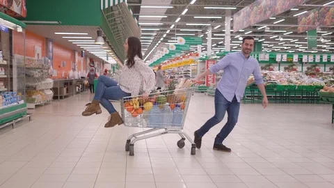 Young couple having fun while choosing food in the supermarket, man pushing Stock Footage 124969699