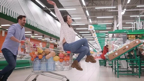 Young couple having fun while choosing food in the supermarket, man pushing Stock Footage 125101159