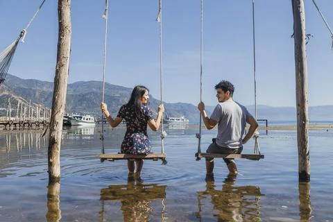 Young couple having fun while swinging in the middle of Lake Atitlan - traveler Stock Photos