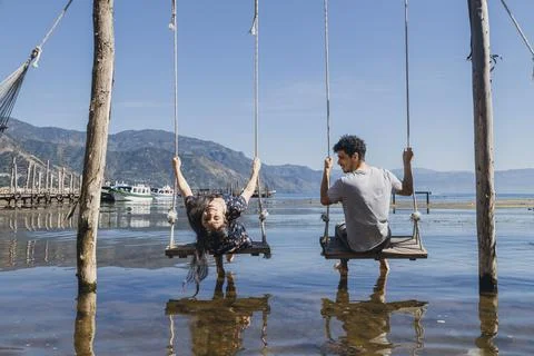 Young couple having fun while swinging in the middle of Lake Atitlan - traveler Stock Photos