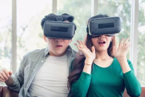 Young Couple Having Fun While Watching Video Via Virtual Reality Together Stock Photos